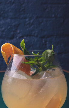Cocktail with orange garnish in dark mood lighting