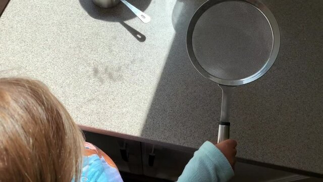 Baking Bread at Home with a Young Child while she plays with the flour sifter