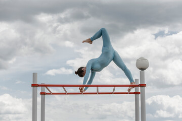 acrobat girl in a blue suit on a horizontal bar
