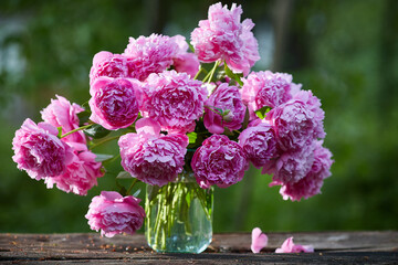 Gorgeous bouquet of pink peonies in a bank on a wooden table on nature © Татьяна Кутина