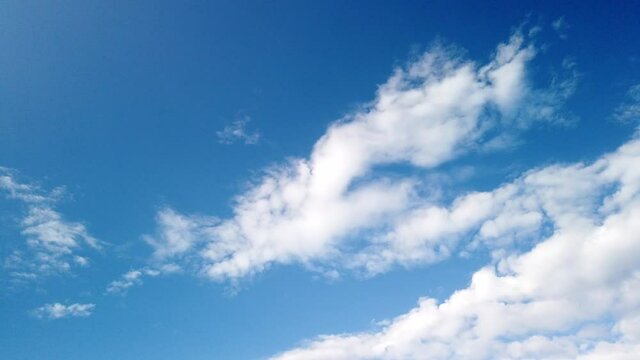 Time-lapse of fluffy clouds moving over blue sky in a sunny day. Nature screensaver timelapse with copy space.
