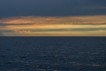 Empty shoot of sunset over sea water, after the thunderstorm. Full of clouds and vibrant colors over horizon. 
