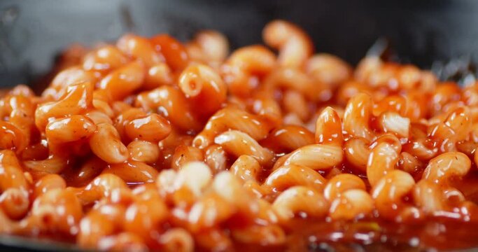 Boiled pasta cavatappi with tomato sauce slowly rotates.