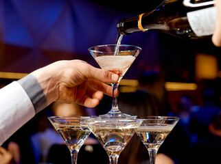 Waiter pours champagne into the upper tower 