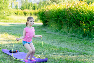 The child goes in for sports in the park. Girl jumping rope