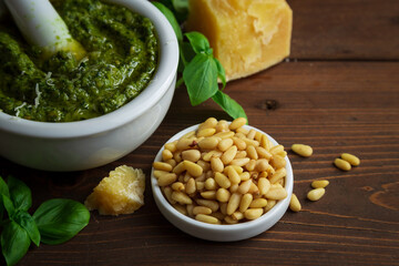Pesto sauce and ingredients for cooking on a wooden table. Fresh basil, parmesan, nuts and olive...