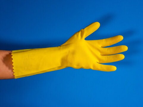 open girl hand with yellow cleaning gloves and blue background