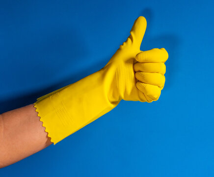 hand of a girl with yellow gloves with thumb up gesture and blue color background
