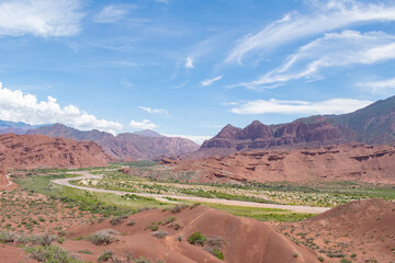 Fototapeta premium Vista panoramica de un valle que se mete entre montañas de color rojizo en un dia soleado
