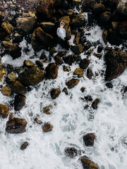 a girl in a dress lies on the rocks by the ocean top view