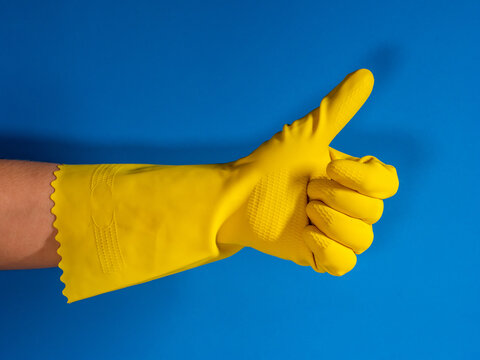yellow gloved hand with thumb up with blue color background