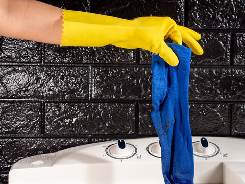 gloved hand pulling a blue sock out of a white washing machine