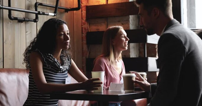 African woman and caucasian man friends talking relaxing in coffeehouse with coffee, multiracial people and diverse couple students share table enjoy communication on date meeting together in cafe