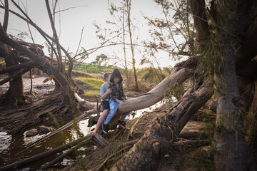 Boys playing on log over river