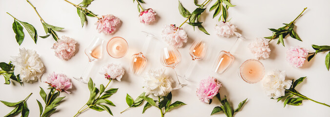 Rose wine variety layout. Flat-lay of rose wine in various glasses and summer blooming peony flowers over white background, top view. Summer drink for party, wine shop or wine tasting concept