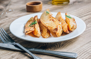 Baked potato fries with sea salt and rosemary on a rustic wooden background.