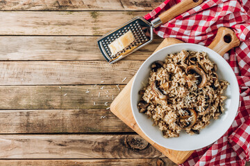 Homemade traditional Italian mushroom risotto on rustic wooden background. Classic Risotto with mushrooms vegetables served on a white plate.