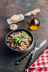 Original italian risotto with mushrooms and parmesan cheese in a dark bowl on a dark background.