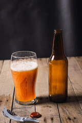 waiter serving craft beer in a glass bottle on a rustic wooden table and dark environment.