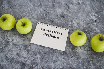Contactless Delivery text on notepad among apples concept of groceries shopping during quarantine or lockdown