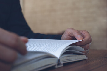 close up of man reading book on table