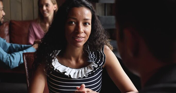 Smiling young african woman talking to man boyfriend during blind date in cafe, happy millennial girl speak to male friend having discussion informal friendly conversation at meeting in public place