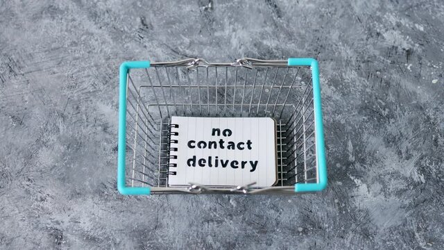 No Contact Delivery text on notepad inside shopping basket symbol of purchases during isolation and lockdown with camera tilting
