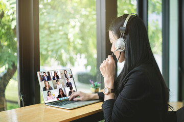 Fototapeta premium Business woman working on laptop computer at home during quarantine for coronavirus. VDO conference call with business partner group. Work from home and social distancing concept.