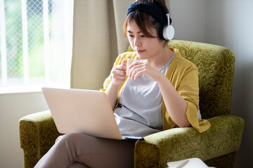 コーヒーを飲みながらPCで動画配信を楽しむ女性