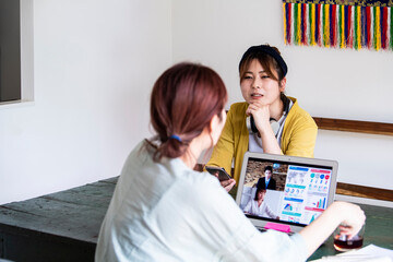 友人と会話をしながら、職場のWEB会議に参加する女性