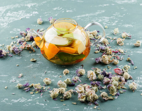 Fruit Infused Water With Dried Flowers In A Teapot On Plaster Background, High Angle View.