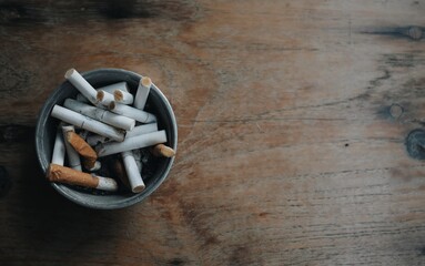 Close up of an ashtray and cigarette butts placed on a wooden table