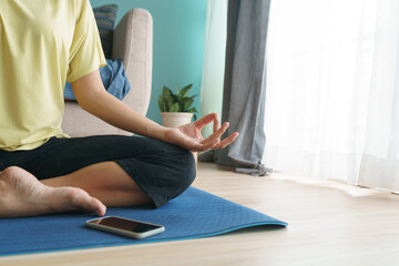 Hand of woman in lotus pose while sitting at mat yoga
