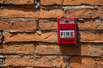 the red fire alarm box on the brick wall