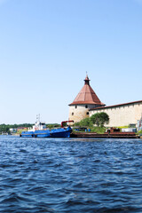 the pier with a ship and medieval Shlisselburg (Oreshek) fortress on the island in Russia