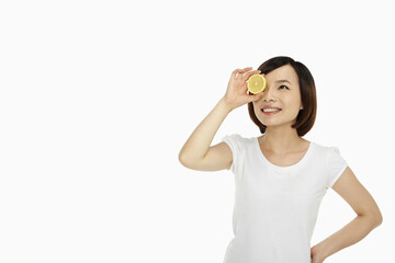 Cheerful woman covering her eye with a lemon