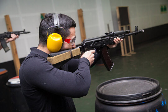A man shoots a gun at a target in a dash with headphones