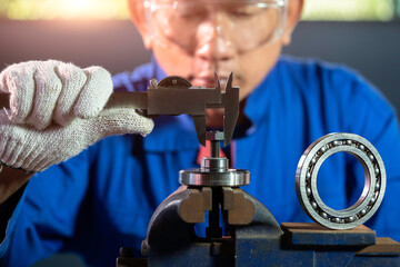 Asian technician engineering measuring ball bearing with vernier calliper