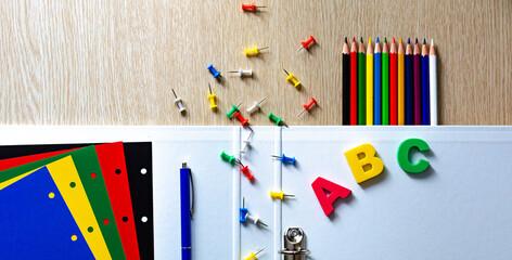 Colorful composition of vibrant color school supplies: colored pencils, papers, pens and english letters on the withe wooden background. Banner. Flat lay. Back to school and education concept.