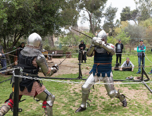 Two knights with swords fight in the ring at the Purim festival with King Arthur in Jerusalem city, Israel
