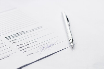 Signature under a business contract agreement with a pen. The signature is fictional.