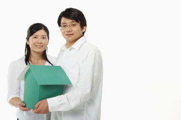 Man and woman holding a cardboard house