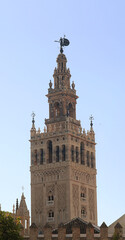 Fototapeta na wymiar Giralda, bell tower of the cathedral of Sevilla with a clear blue sky in the background - vertical postcard