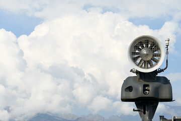 nature landscape and travel concept - snow cannon in mountains against the blue sky with clouds in early autumn