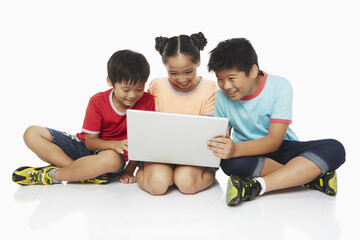 Fototapeta premium Three children using a laptop together