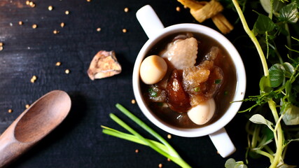 Fish maw in chicken broth on a black wooden plate background