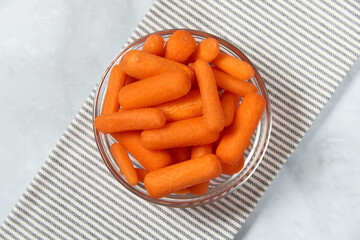 nature, diet and healthy food concept - top view of fresh baby peeled carrots on the marble background and striped napkin. Copy space. Flat lay