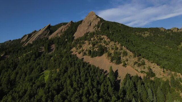 flatiron mountains boulder Colorado with morning sun and green trees against blue sky background