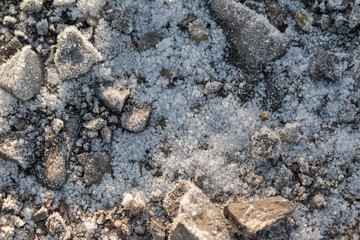 Stones covered with coarse snow and ice for backdrop. Grainy snowflakes and patterns of ice on a rock.