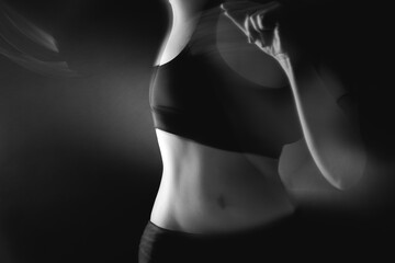 Naklejka premium Feminine energy. Body vitality. Defocused woman silhouette in black athletic top on gray background.